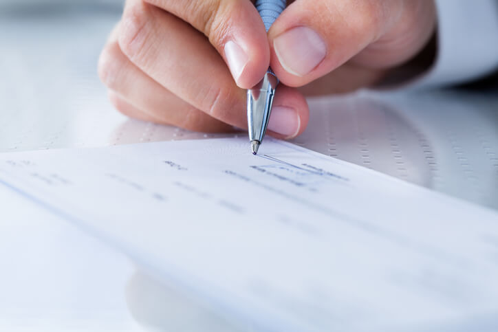 Male payroll clerk filling a check in an office after career training in BC