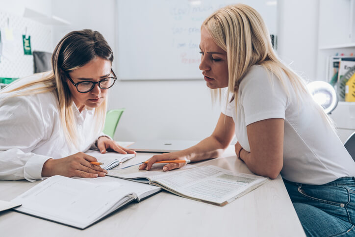 An educational Assistant reviewing lesson materials with a teacher, highlighting educational assistant qualifications in BC